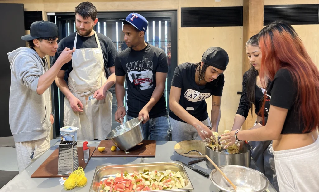 eat club cooking and food education in action, five young people and a session leader cooking during eat club's hospitality kickstart course with king's trust