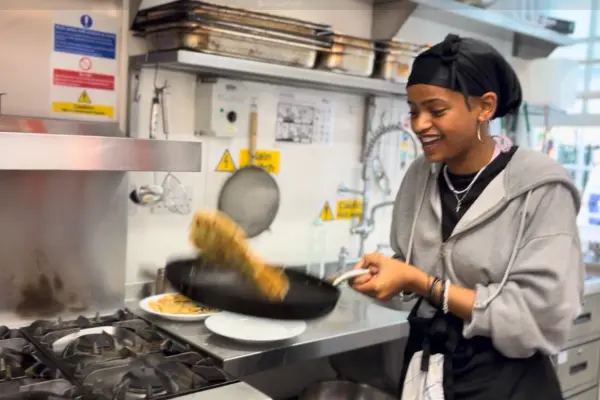 eat club cooking and food education course participant flipping food on the stove